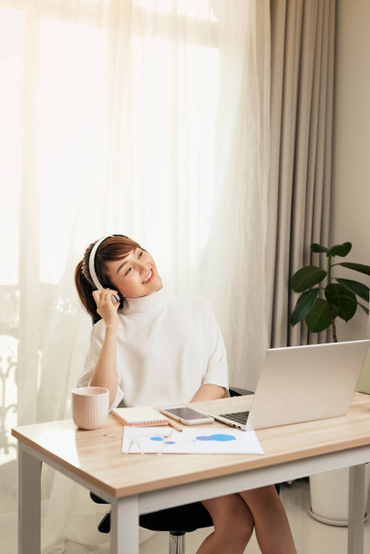 Beautiful young Asian woman listening to music at working space at home. - Foto, imagen