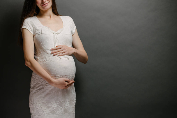 Pregnant woman portrait. She is holding a belly and smiling - Φωτογραφία, εικόνα