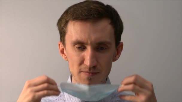 Close-up portrait of a young man putting on a medical mask. - Materiał filmowy, wideo