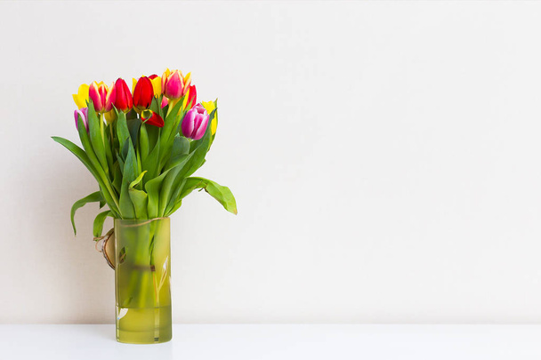 Bouquet of tulips in a vase on a light background - Zdjęcie, obraz