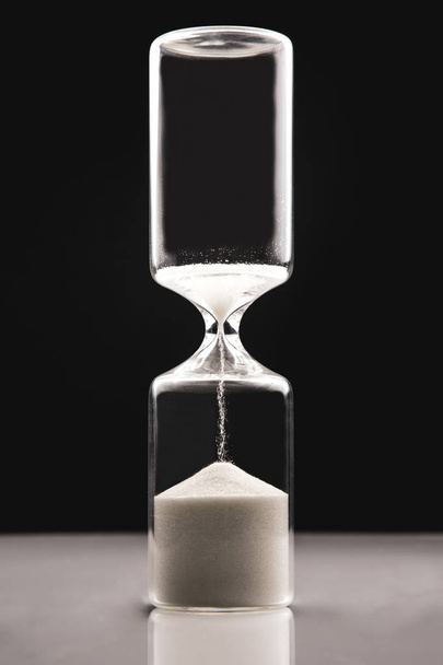 Hourglass on a dark background. Time is money. Business solution - Photo, Image