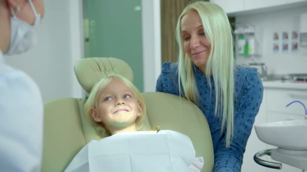 Mutter sitzt bei ihrer Tochter und spricht mit Zahnarzt - Filmmaterial, Video