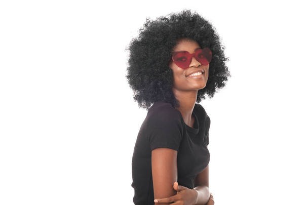 Chica afro sonriente en gafas rojas y camisa negra
. - Foto, Imagen