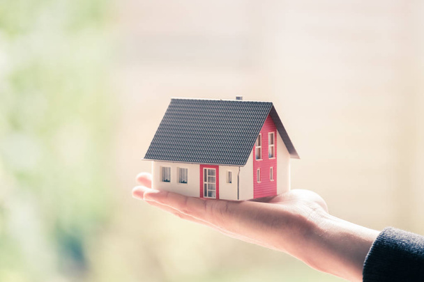 New home and house concept: Red house model outdoors in male hand - Photo, Image