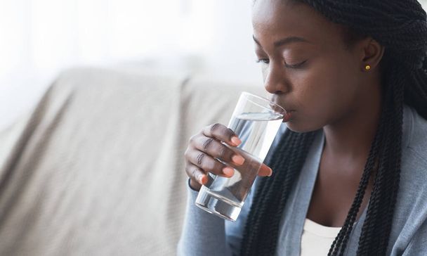 Жага чорна дівчина п'є чисту воду зі скла вдома
 - Фото, зображення