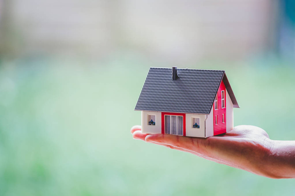 New home and house concept: Red house model outdoors in male hand - Foto, Imagen