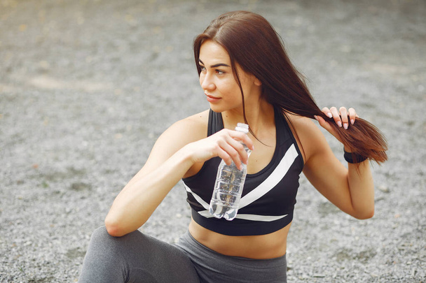 Sports girl in a sports clothes drinking a water - Foto, imagen