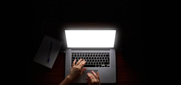 hacker aéreo no capô trabalhando com laptop e telefone celular digitando texto no quarto escuro
 - Foto, Imagem