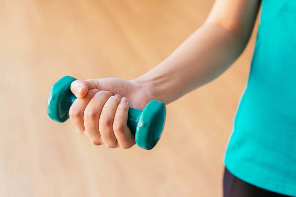 Stock photo of a young woman holding a dumbbell - Foto, imagen