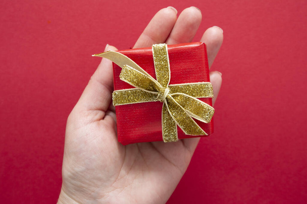 Top view of female hands holding gift box with red ribbon bow isolated over flat lay background, copy space. - Φωτογραφία, εικόνα