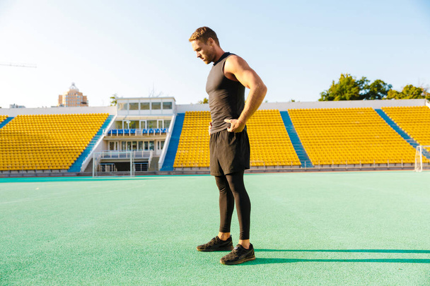 Image of caucasian man standing at sports ground while doing wor - 写真・画像