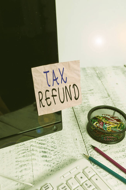 Handwriting text writing Tax Refund. Concept meaning refund on tax when the tax liability is less than the tax paid Note paper taped to black computer screen near keyboard and stationary. - 写真・画像