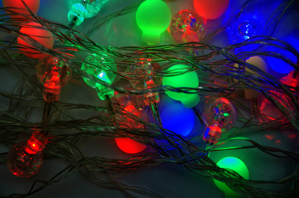 Πρωτοχρονιάτικες γιρλάντες με πολύχρωμες λάμπες σε σκούρο φόντο, αφηρημένο φόντο με γιρλάντα της Πρωτοχρονιάς - Φωτογραφία, εικόνα