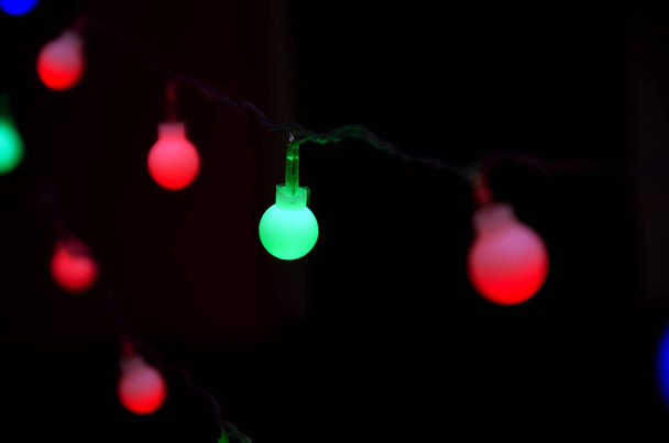 Новогодние гирлянды с разноцветными лампочками на тёмном фоне, абстрактный фон с новогодней гирляндой
 - Фото, изображение