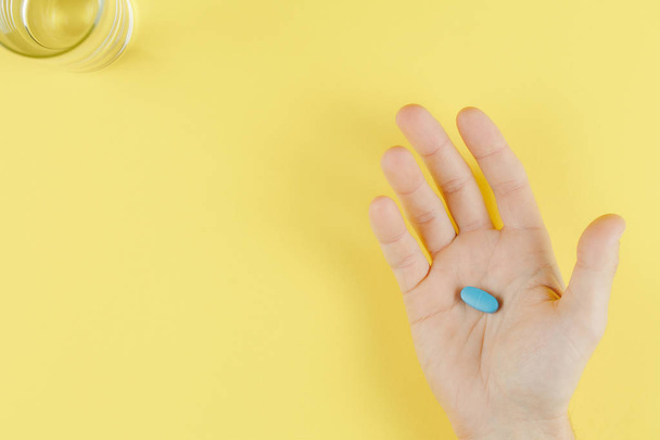 modrá pilulka v ruce na žlutém zobrazení nahoře - Fotografie, Obrázek