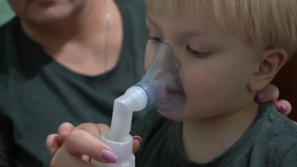 Een kind van drie jaar oud dat een zuurstofmasker inademt. Inademing van de luchtwegen. Masker inhalator. - Video