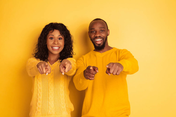 Young emotional african-american man and woman on yellow background - Valokuva, kuva
