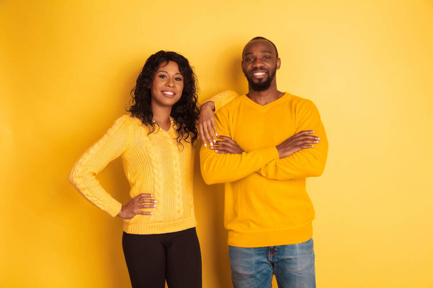 Young emotional african-american man and woman on yellow background - Foto, Imagen