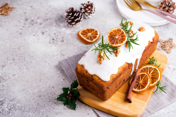 Fruit loaf cake dusted with icing, nuts and dry orange on stone background. Christmas and Winter Holidays - 写真・画像