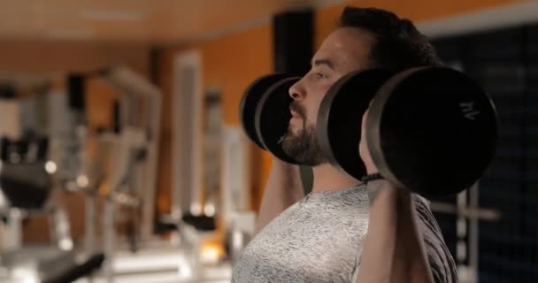 Man lifting dumbbells in a gym making exercise for deltoids - Metraje, vídeo