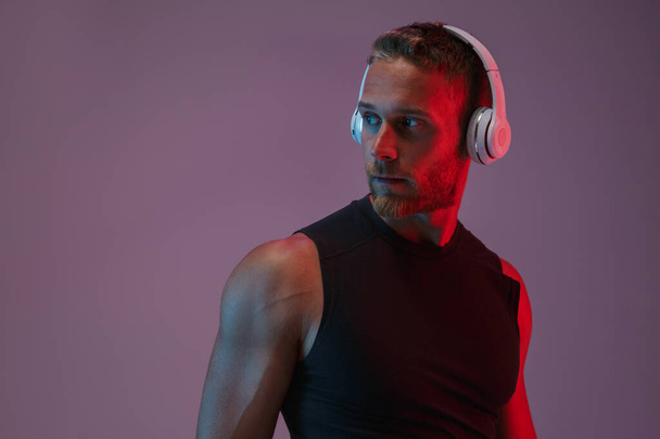 Sports man posing isolated listening music with headphones. - Photo, Image