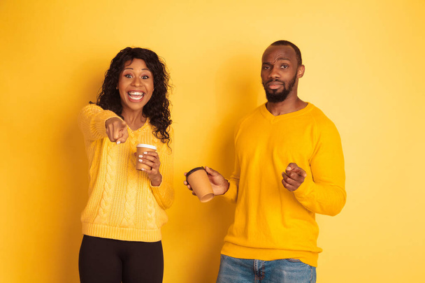 Young emotional african-american man and woman on yellow background - Фото, изображение