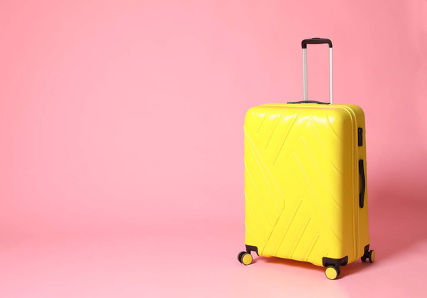 Stylish yellow suitcase on pink background. Space for text - Zdjęcie, obraz