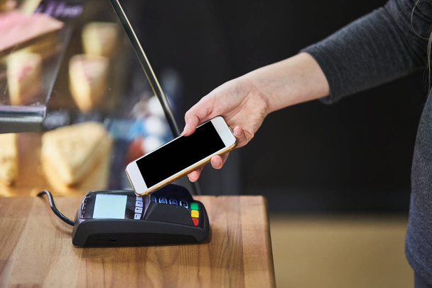 Afsluiten hand betalen bestelling met creditcard op betaalterminal in de coffeeshop - Foto, afbeelding