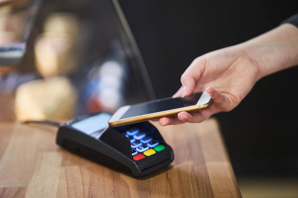 Κοντινό πλάνο εντολή πληρωμής με πιστωτική κάρτα στο τερματικό πληρωμής στην καφετέρια - Φωτογραφία, εικόνα