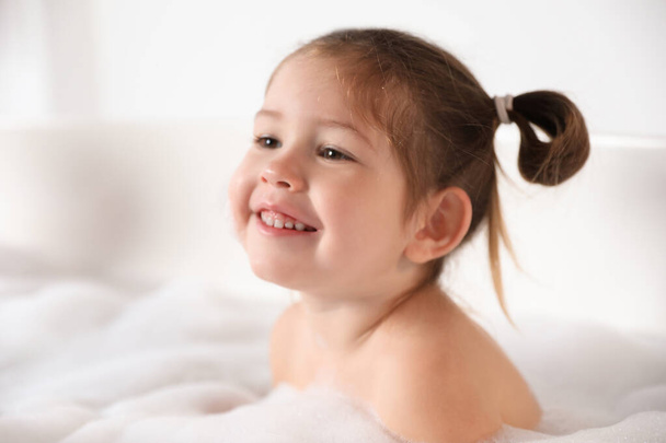 Cute little girl taking bubble bath at home - Фото, изображение