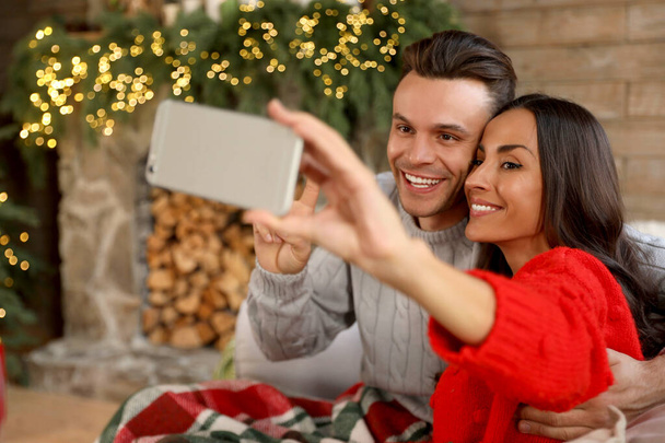 Happy young couple taking selfie in living room decorated for Christmas - Valokuva, kuva