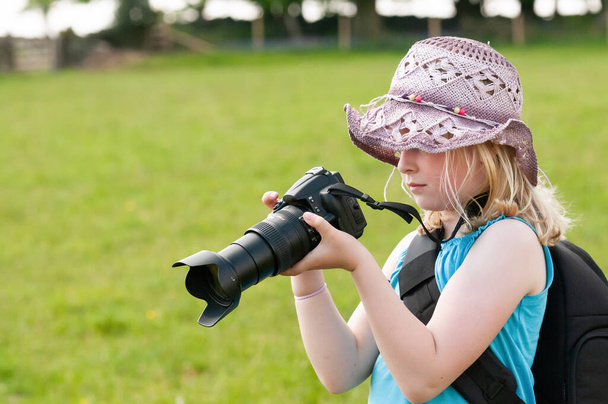 Mladá dívka v floppy klobouk pomocí velkého digitálního fotoaparátu - Fotografie, Obrázek