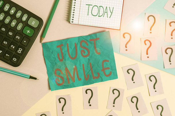 Handschrift tekst schrijven Just Smile. Concept betekent veronderstellen een gezichtsuitdrukking die plezier of amusement aangeeft Wiskunde spullen en schrijfapparatuur boven pastelkleuren achtergrond. - Foto, afbeelding