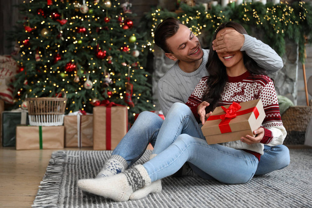 Happy couple with gift box in living room decorated for Christmas - Fotó, kép