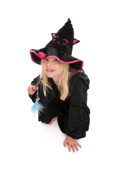 Young blonde girl in witches cloak and hat crouched on floor wit - Zdjęcie, obraz
