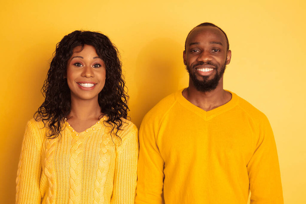 Young emotional african-american man and woman on yellow background - Foto, imagen