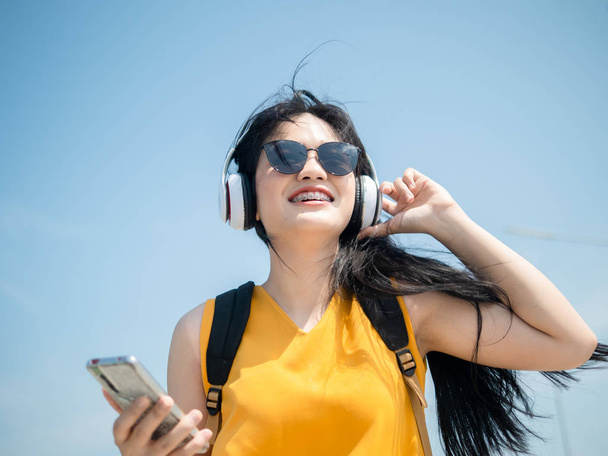 Happy Asian woman with backpack using headphone on the beach, li - Foto, Imagem