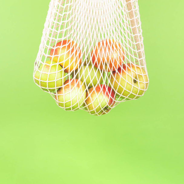 Jabłka w bawełnianej torbie na zakupy wielokrotnego użytku na zielonej kropli - Zdjęcie, obraz
