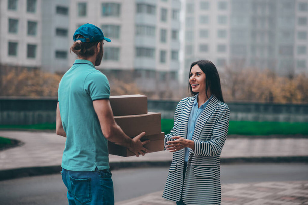 Businesswoman wearing jacket meeting delivery man outside - Valokuva, kuva