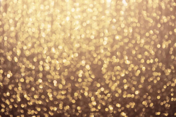 Golden background. Glowing Christmas lights backdrop. Defocused glitter sparkles - Photo, image