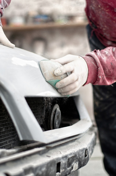 Mechanic prepairing the body of a car for a paint job by appling the first layer of polish - Fotoğraf, Görsel