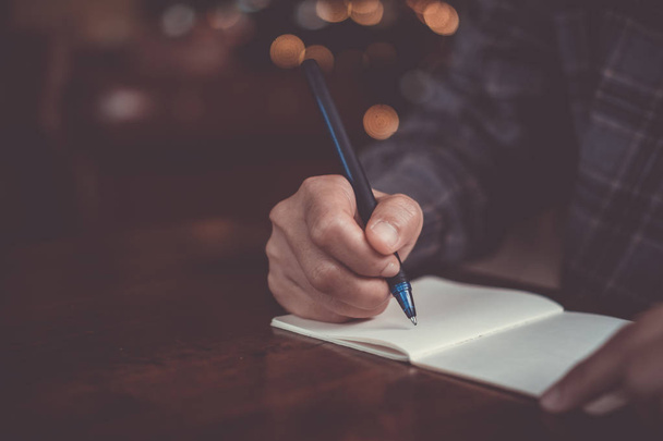 Nő kézzel írja le a kis fehér jegyzetfüzet jegyzetfüzetet, hogy egy megjegyzés, hogy ne felejtsük el, vagy hogy nem lista terv. - Fotó, kép