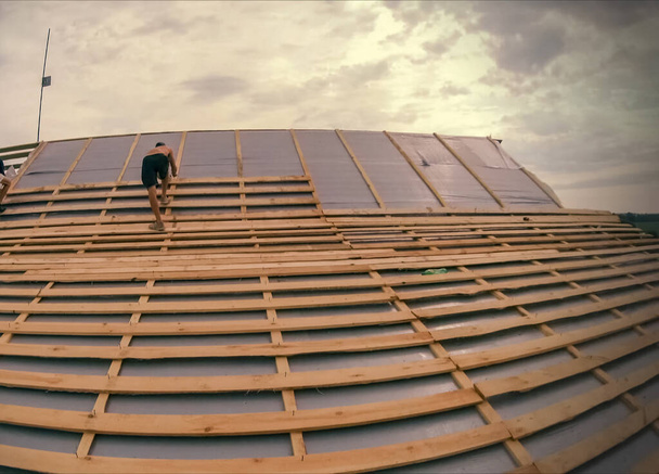 家に屋根を設置する。労働者が屋根を作る. - 写真・画像