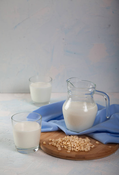 Vegetarian pine nut milk in glass cups and jug, on white background. Vertikal - Foto, afbeelding