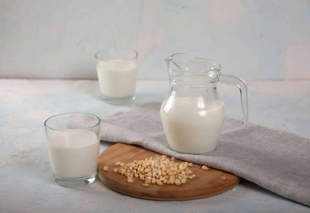 Vegetarian pine nut milk in glass cups and jug, on white background. Copy spais. horizontal - Foto, afbeelding