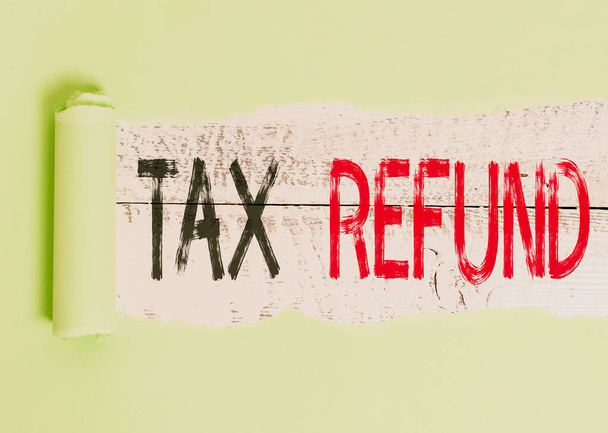 Conceptual hand writing showing Tax Refund. Business photo showcasing refund on tax when the tax liability is less than the tax paid Cardboard which is torn placed above a wooden classic table. - Photo, Image