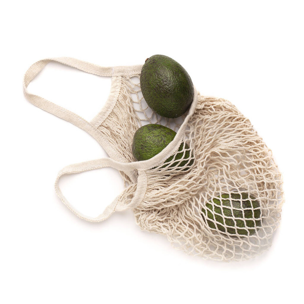 Healthy fresh avocado in zero waste net bag isolated on white - 写真・画像