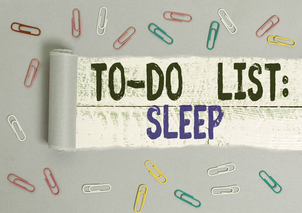 Handwriting text To Do List Sleep. Concept meaning Things to be done Priority object is to take a rest Paper clip and torn cardboard placed above a wooden classic table backdrop. - Photo, Image