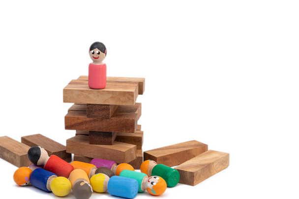 Ένα ξύλινο παιχνίδι ξύλινο στέκεται σε έναν ψηλό πύργο και κοιτάζει ένα μεγάλο αριθμό ανθρώπων που την υπακούν. Η έννοια της κυβερνώσας γυναίκας και του δικτάτορα. Εικόνες του πληθυσμού και του προέδρου - Φωτογραφία, εικόνα