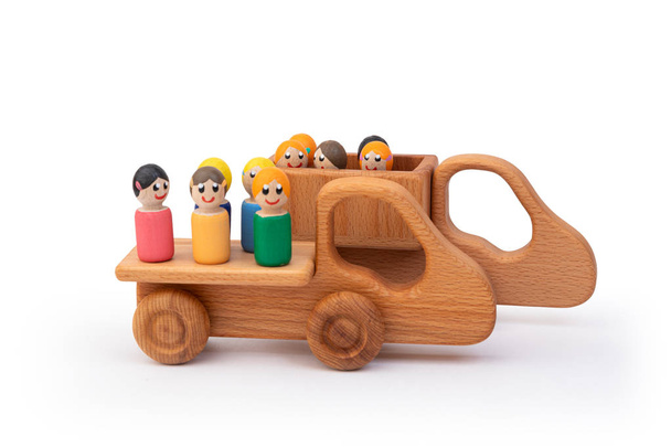 Houten speelgoed vrachtwagens aangedreven door veelkleurige mannen op een witte geïsoleerde achtergrond. Concept bouwplaats - Foto, afbeelding